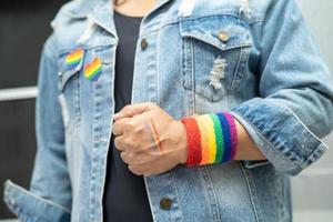 dama asiática con pulseras de la bandera del arco iris, símbolo del mes del orgullo lgbt celebran anualmente en junio las redes sociales de gays, lesbianas, bisexuales, transgénero, derechos humanos. foto