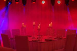 Luxurious wedding table with decor, with silver candlesticks, candles and flowers in blue light. Selective photo