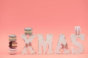 The wooden word xmas with colorful macaroons or macarons on pink background photo