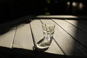 a glass of water on a white table with rays of the sun with nature background photo