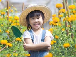 Cute little girl in hat holding garden tool shovel for planting flowers in the garden. A child helps mom in the garden, a little gardener.