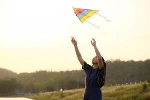 Young woman flying a kite by the lake at sunset. photo