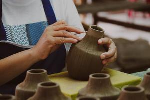Close-up of a woman's hand making patterns on a clay vase in a pottery workshop. Process of making a ceramic vase. handicraft and small business concept. photo