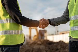 Ingenieros hombre apretón de manos en el sitio de construcción. trabajador y gerente de construcción dándose la mano mientras trabaja para el trabajo en equipo. foto