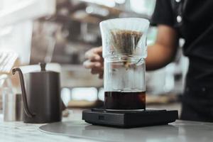 barista haciendo café vertiéndolo en la cafetería... cerca de las manos barista para hacer un café por goteo. concepto de cafetería foto