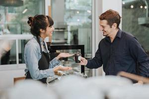 mujer caucásica barista toma el pedido del cliente en la cafetería. barista femenina que usa una tableta digital para tomar el pedido. concepto de propietario de café. foto