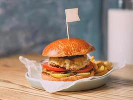 light beer and fat burger with meat, cheese, tomato, pickle and french fries on the table photo