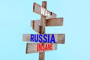 Wooden road sign with words war, russia, insane, sanctions, aggression, regress photo