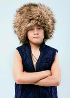 Portrait of young stylish boy in fur hat on light background photo