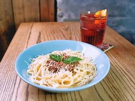 pasta bolognese in the plate and old fashioned cocktail on the table in the bar photo