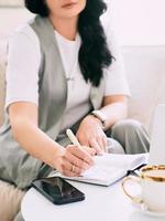 woman sitting on the sofa and making notes in her notebook. Business, analytics, education photo