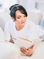 hermosa mujer en el sofá leyendo un libro. tiempo libre, educación, concepto de autodesarrollo. foto