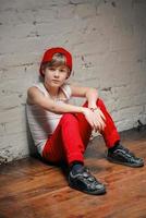 Portrait of cool young hip hop boy in red hat and red pants and white shirt in the loft photo