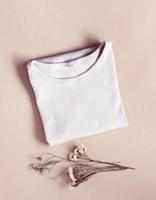 Light folded T-shirt on beige background. Mockup top view vertical location photo