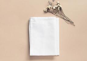 Stack of fabrics over beige background. Flat lay with white folded cloth for mockup photo