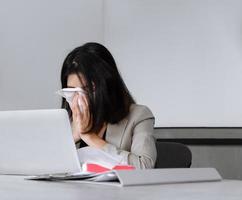 Sick business woman sneezing while working in meeting room. Working and seasonal inflection concept photo