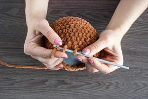 The process of knitting children toy from plush yarn. Knitting head. Handmade photo