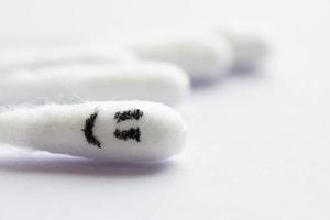 Close-up of cotton swabs with a smiling emoticon on a cotton swab in the foreground. Happiness concept photo