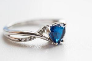 Close up silver ring with blue heart on white background photo
