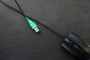 Fixed USB mouse cable wrapped in green electrical tape on a black background. E-waste concept photo