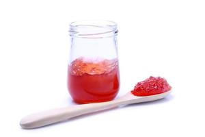 Red jam in jars and wooden spoons set on a white background. photo