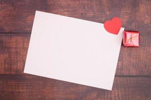 Paper heart with empty boxes and paper on the wooden floor photo