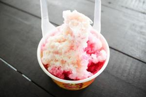 postre de nieve helada con cuchara de plástico en el suelo de madera foto