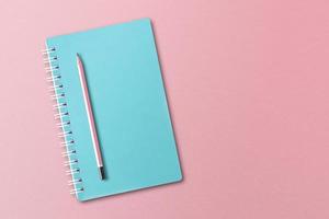 Blue notebook with pencils placed on pink background. photo