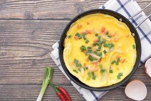 Omelette in a pan that is placed on a wooden background photo