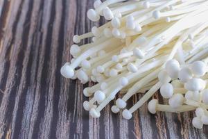 Golden needle mushroom located on wooden background photo