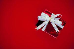 Gift Box with a white ribbon on a red background Close up view of a high resolution product. photo