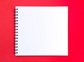 Blank notebook on red ground for writing and design of Christmas photo