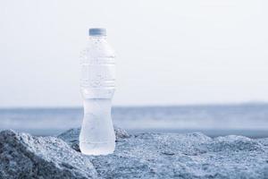 Bottles with clean water on the rocks along the outdoor beach photo