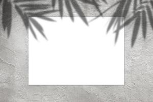 Empty white horizontal rectangular poster mockup with light shadow on gray concrete wall background. photo