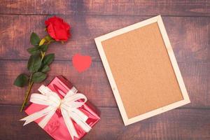 rosas y corazones rojos con cajas de regalo y marcos en blanco sobre suelos de madera foto