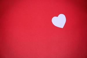 White heart-shaped paper on a red background with the concept Valentines Day photo