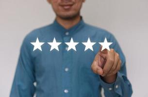 Businessmen wearing a light blue shirt to selecting the level of satisfaction score icons with copy space. Customer service experience and business satisfaction survey concept photo