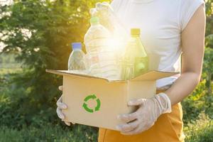 woman picking up garbage plastic bottles into a box for recycling concept photo