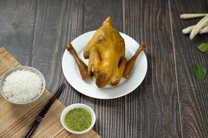 Roasted chicken with a golden crust with vegetables and sauces on a woodle table photo