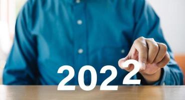 Successful international financial investment concept with business person holding glowing in 2022 sign. new business year changing and start new target concept. photo