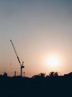 Abstract Industrial background with construction cranes silhouettes over amazing sunset sky photo