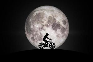 Silhouette of a bike on sky background on full moon.Elements of this image furnished by NASA. photo