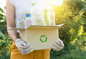 woman picking up garbage plastic bottles into a box for recycling concept photo