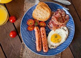 English breakfast - toast, egg, bacon and vegetables in a rustic style on wooden background photo