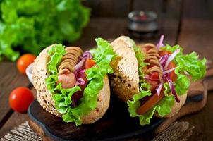 Perrito caliente con salsa de tomate mostaza y lechuga sobre fondo de madera. foto