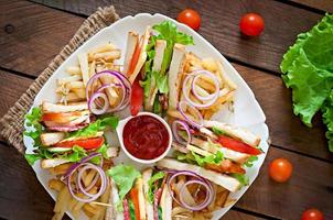 Club sandwich with cheese, cucumber, tomato, smoked meat and salami. Served with French fries. photo