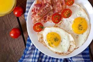 English breakfast - toast, egg, bacon and vegetables in a rustic style on wooden background photo