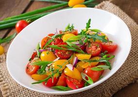 Salad of fresh cherry tomatoes with onion and arugula photo