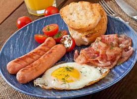 English breakfast - toast, egg, bacon and vegetables in a rustic style on wooden background photo