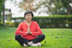 Senior asian woman practicing yoga lesson, breathing, meditating in garden. Working out, Well being, wellness concept photo